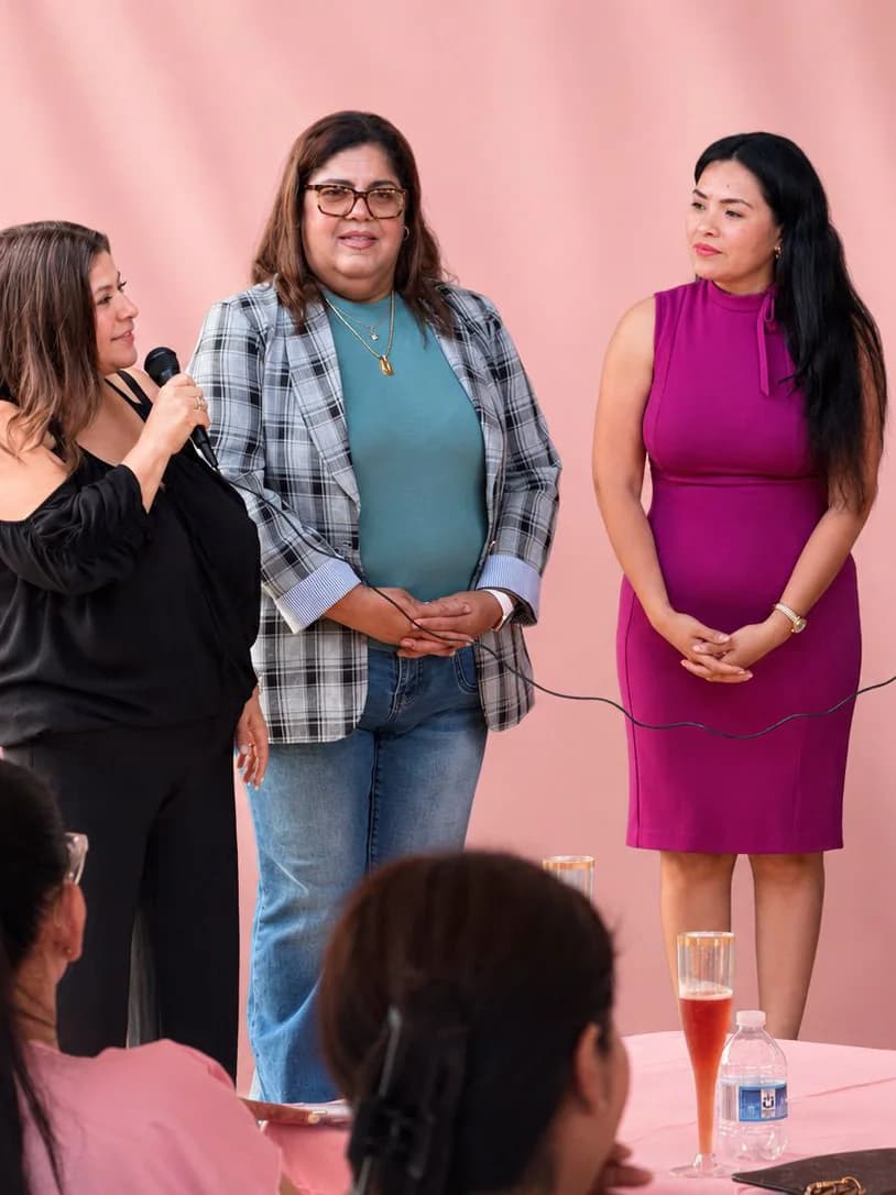 A presentation at the anniversary, microphone in hand against the pink backdrop